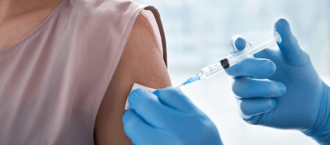 Medical vaccination in a person's upper arm with syringe and gloved hands