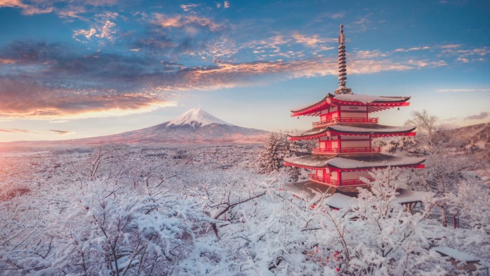 Verschneite Pagode mit Blick auf den Fuji bei Sonnenuntergang in Japan