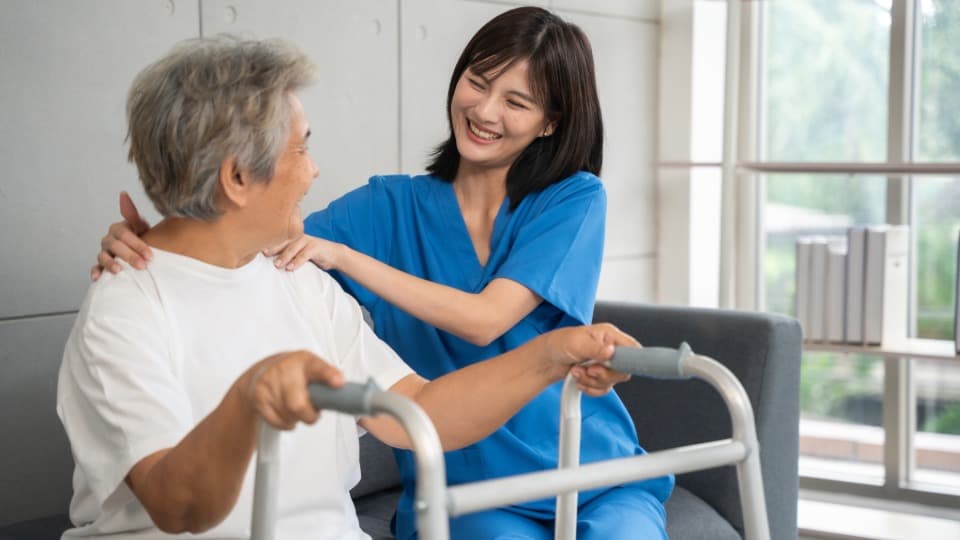 Eine Krankenpflegerin kümmert sich um eine ältere philippinische Patientin